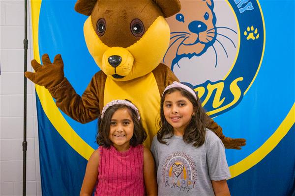 two girls and otter mascot smiling